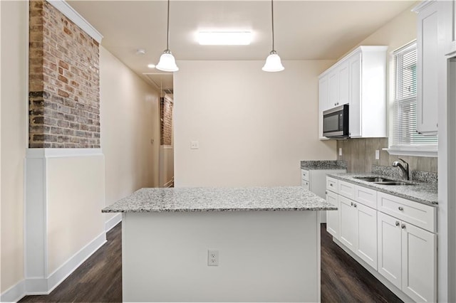 391214 Thalia St, New Orleans, LA 70125 - kitchen featuring stainless steel microwave, a kitchen island, white cabinets, dark wood finished floors, and a sink