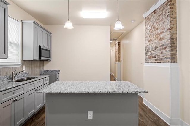 391214 Thalia St, New Orleans, LA 70125 - kitchen featuring stainless steel microwave, gray cabinets, dark wood-style floors, a sink, and hanging light fixtures