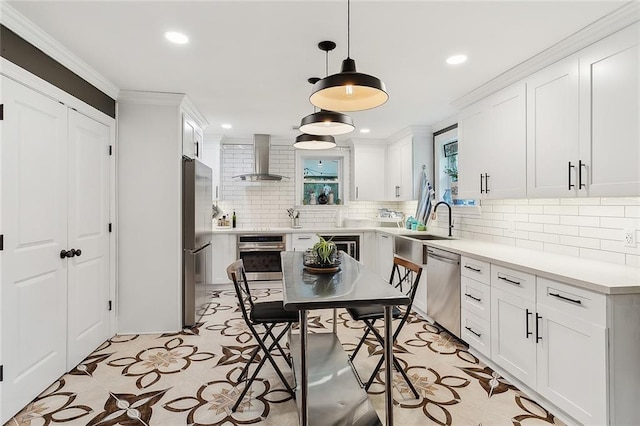 kitchen with wall chimney exhaust hood, white cabinets, backsplash, and appliances with stainless steel finishes