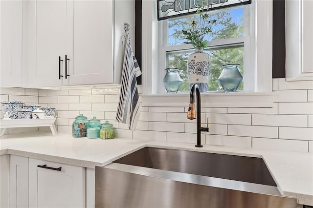 details with white cabinetry, tasteful backsplash, light stone counters, and a sink