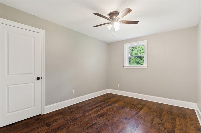empty room with ceiling fan, dark wood-style floors, and baseboards