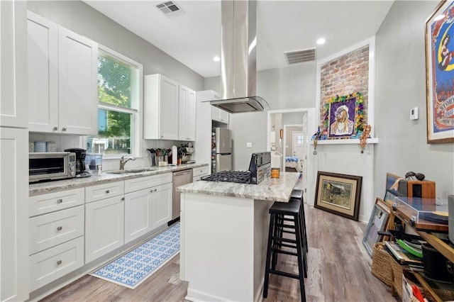 202729 Cambronne St, New Orleans, LA 70118 - kitchen with visible vents, white cabinets, a sink, appliances with stainless steel finishes, and a kitchen breakfast bar