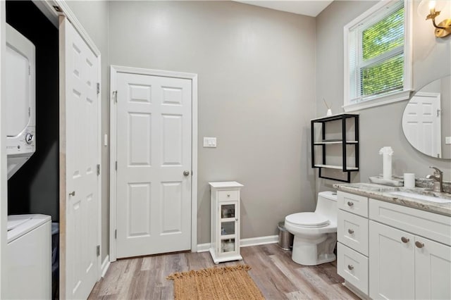 202729 Cambronne St, New Orleans, LA 70118 - bathroom featuring stacked washing maching and dryer, vanity, toilet, and wood finished floors