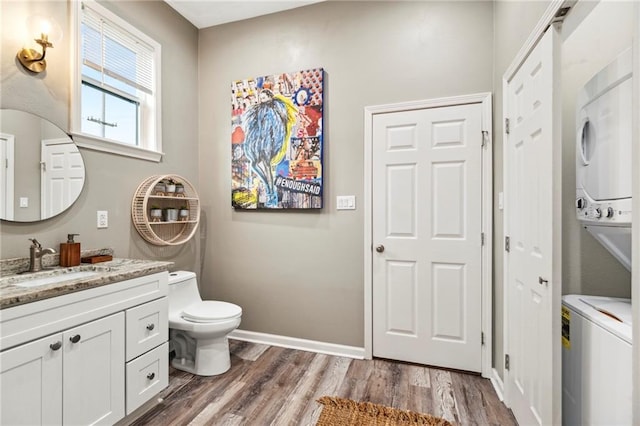 202729 Cambronne St, New Orleans, LA 70118 - half bathroom featuring vanity, baseboards, toilet, stacked washing maching and dryer, and wood finished floors