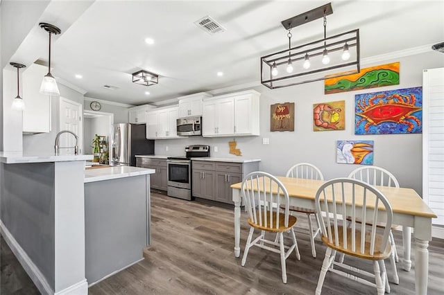 kitchen featuring appliances with stainless steel finishes, wood finished floors, ornamental molding, and recessed lighting