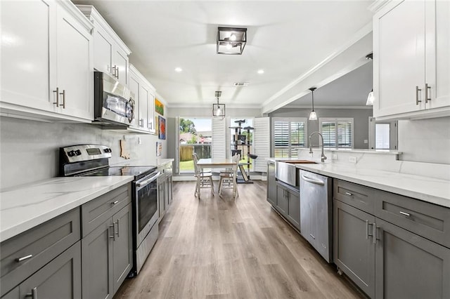kitchen with gray cabinetry, ornamental molding, and appliances with stainless steel finishes
