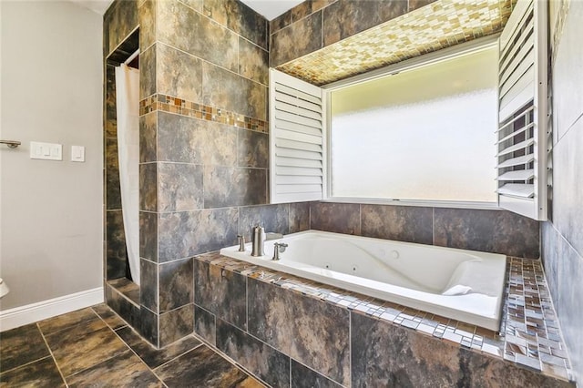 full bathroom with a jetted tub and baseboards