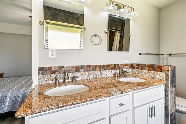 bathroom featuring toilet, double vanity, and a sink