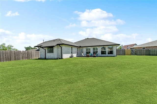 back of property featuring brick siding, a fenced backyard, and a lawn