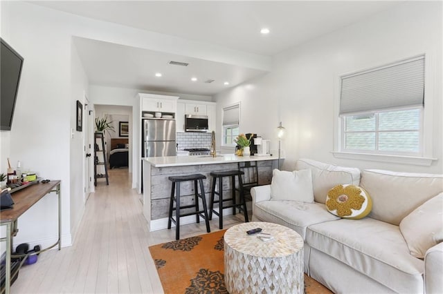living room with recessed lighting, light wood finished floors, and visible vents