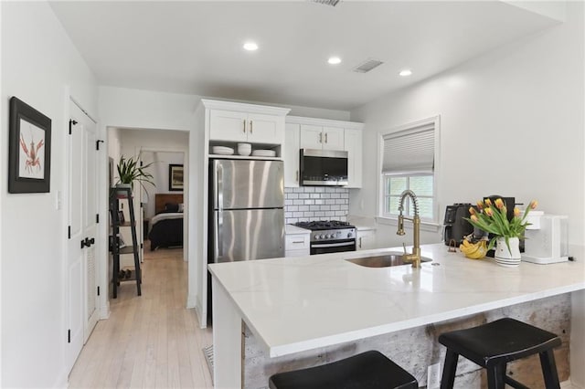 kitchen featuring recessed lighting, white cabinets, visible vents, appliances with stainless steel finishes, and a sink
