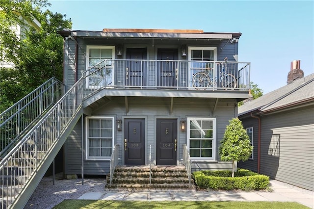 view of front of property with stairs and a balcony