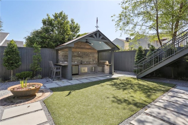 exterior space with an outdoor kitchen, stairs, a patio area, a fenced backyard, and a sink
