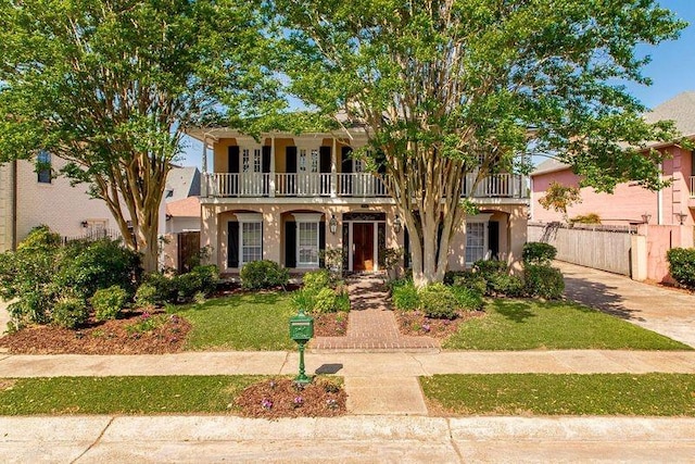 4516 Beau Lac Ln, Metairie, LA 70002 - view of front of home featuring a balcony, fence, stucco siding, and a front lawn