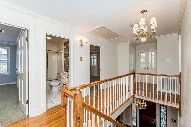 4516 Beau Lac Ln, Metairie, LA 70002 - hall featuring an inviting chandelier, an upstairs landing, french doors, attic access, and crown molding