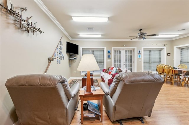 living room featuring french doors, crown molding, a ceiling fan, visible vents, and light wood finished floors
