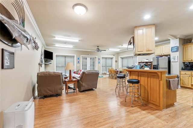 kitchen with open floor plan, ornamental molding, stainless steel fridge, and a kitchen breakfast bar