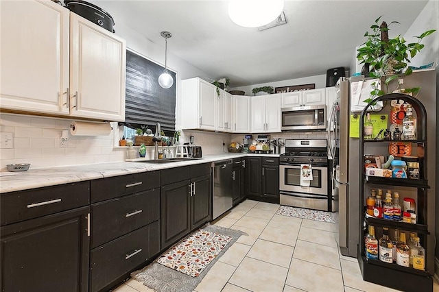 313 Alpaca Dr, Arabi, LA 70032 - kitchen with stainless steel appliances, white cabinets, tasteful backsplash, and light tile patterned floors