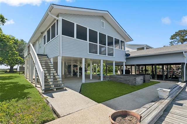 rear view of house featuring a sunroom, a carport, stairway, and a lawn