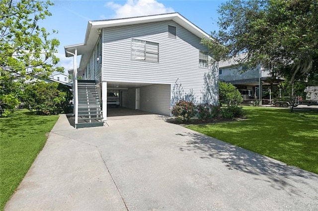 view of side of property with a carport, driveway, a yard, and stairs