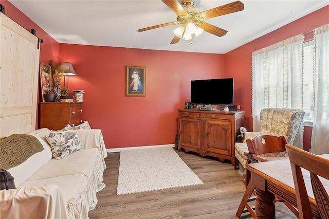 living room with baseboards, a ceiling fan, and wood finished floors