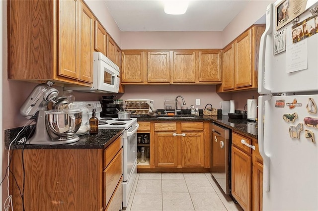 kitchen featuring brown cabinetry, a sink, light tile patterned floors, and white appliances