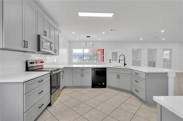 7721 Bullard Ave, New Orleans, LA 70128 - kitchen featuring a peninsula, appliances with stainless steel finishes, light countertops, a sink, and gray cabinetry