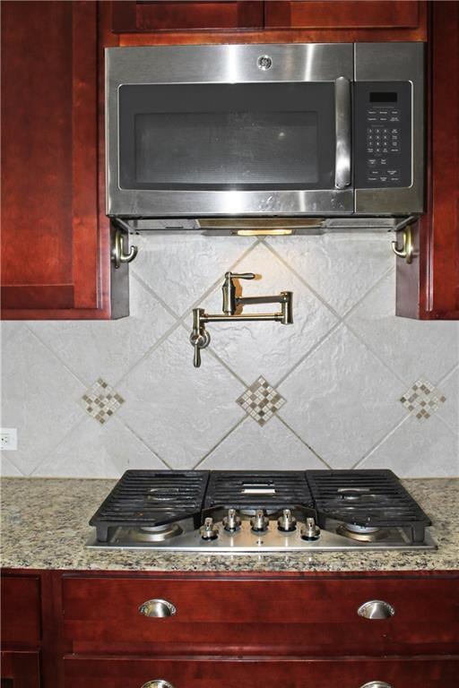23620 Madisonville Ct, Ponchatoula, LA 70454 - interior details featuring light stone counters, dark brown cabinets, stainless steel appliances, and tasteful backsplash