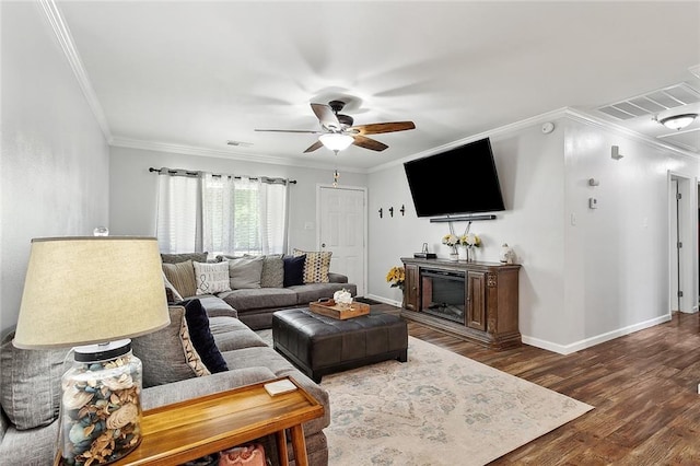 living room with wood finished floors, visible vents, crown molding, baseboards, and ceiling fan