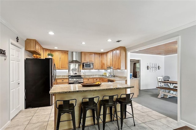 kitchen featuring stainless steel appliances, wall chimney range hood, ornamental molding, light tile patterned floors, and a sink