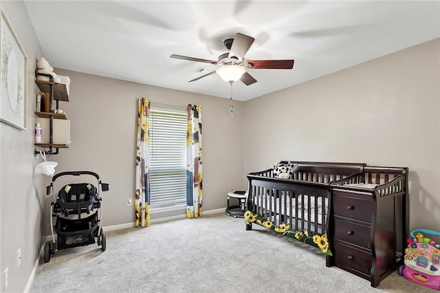 bedroom with a nursery area, carpet floors, baseboards, and ceiling fan
