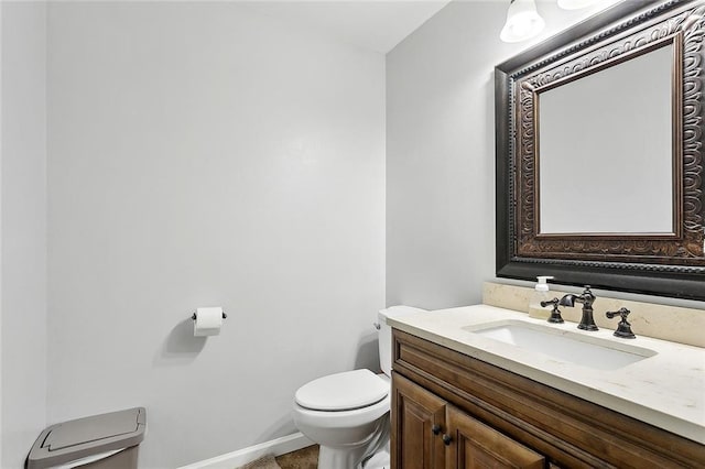 half bathroom with baseboards, toilet, and vanity