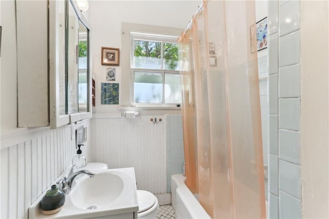 full bath with toilet, shower / tub combo with curtain, wainscoting, vanity, and tile patterned floors