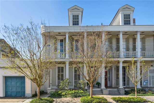 greek revival house featuring a garage and a balcony