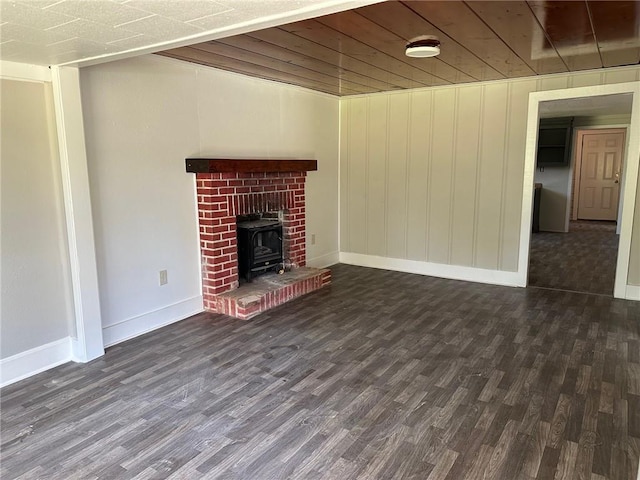 25821 Elsie Gill Rd, Holden, LA 70744 - unfurnished living room featuring a wood stove, baseboards, and dark wood finished floors