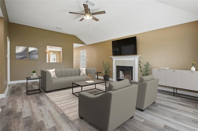 living room featuring visible vents, lofted ceiling, baseboards, light wood-type flooring, and a ceiling fan