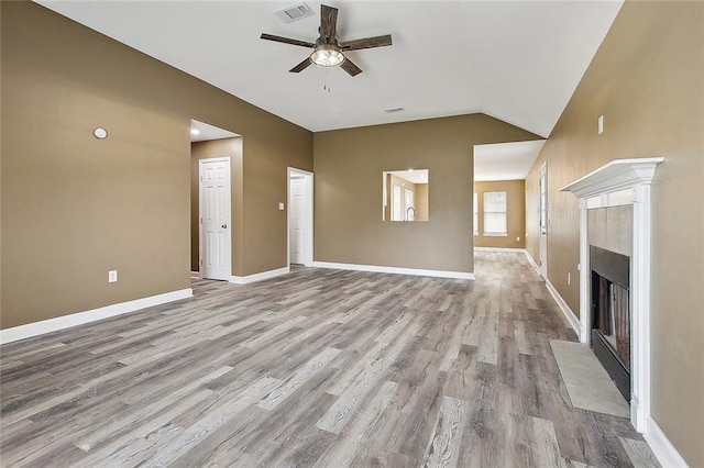 unfurnished living room with ceiling fan, visible vents, a tiled fireplace, wood finished floors, and lofted ceiling