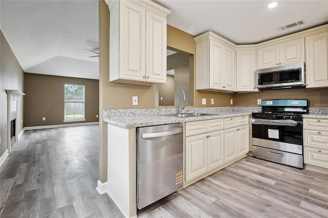 kitchen featuring visible vents, a sink, lofted ceiling, light wood-style floors, and stainless steel appliances