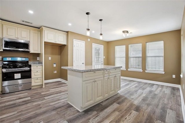 kitchen featuring visible vents, baseboards, light wood-type flooring, cream cabinetry, and appliances with stainless steel finishes