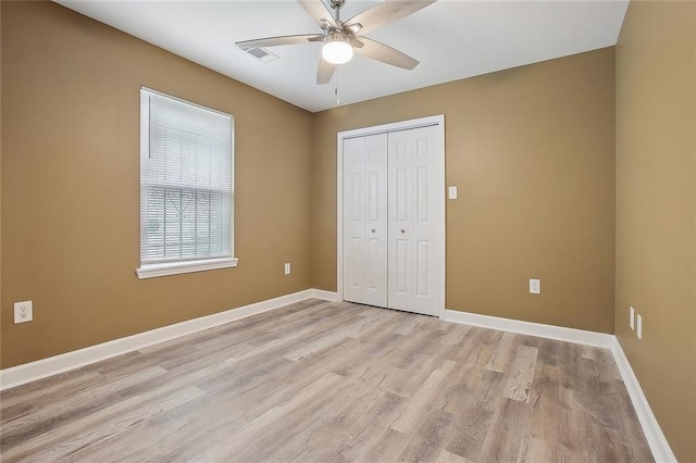unfurnished bedroom featuring ceiling fan, light wood-style floors, baseboards, visible vents, and a closet