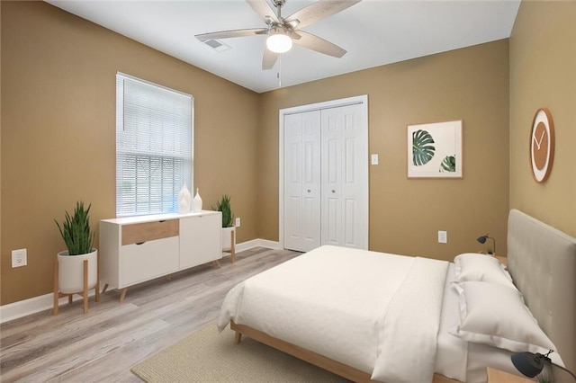 bedroom featuring a ceiling fan, visible vents, light wood-type flooring, baseboards, and a closet