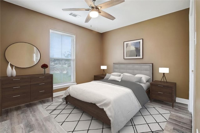 bedroom featuring light wood-style floors, baseboards, multiple windows, and visible vents