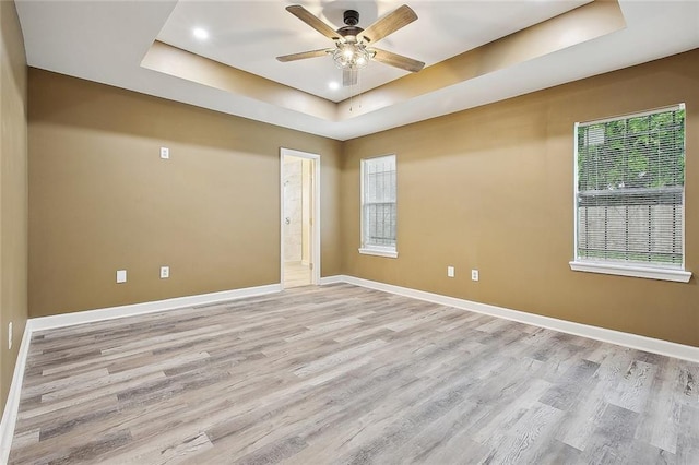 unfurnished room featuring baseboards, light wood-style floors, recessed lighting, a raised ceiling, and a ceiling fan