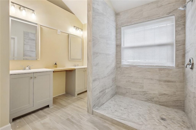 bathroom with vanity, vaulted ceiling, and tiled shower