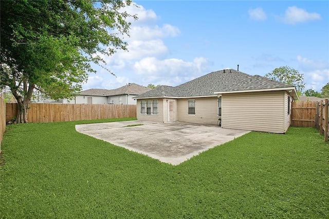 back of house featuring a fenced backyard, a shingled roof, a yard, and a patio area