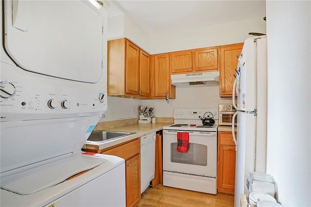 4018 Pitt St, New Orleans, LA 70115 - kitchen with light wood-style floors, white appliances, under cabinet range hood, light countertops, and stacked washer and clothes dryer