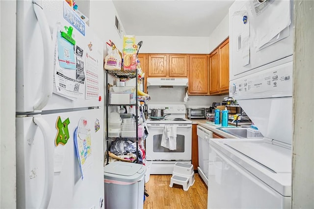 4018 Pitt St, New Orleans, LA 70115 - kitchen with white appliances, stacked washer / dryer, under cabinet range hood, light countertops, and brown cabinets