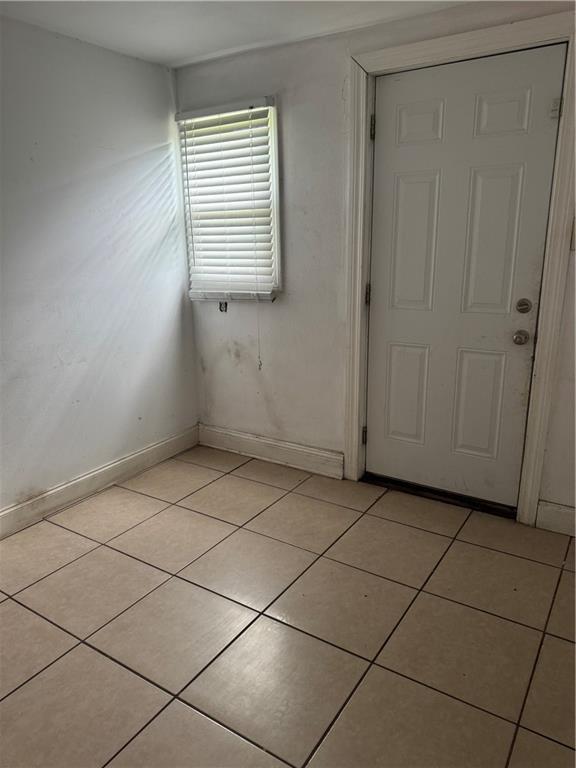 unfurnished room featuring light tile patterned floors and baseboards
