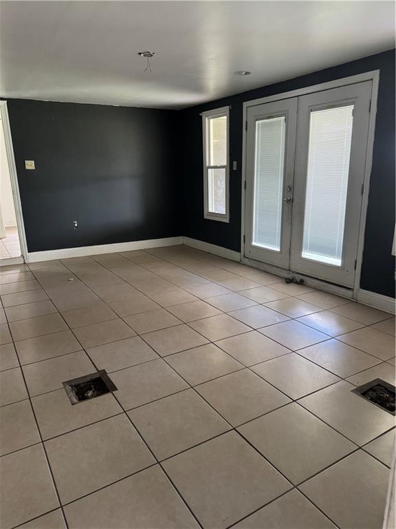 interior space with light tile patterned floors, french doors, and baseboards