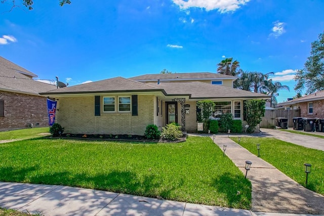 view of front of home with a front yard, fence, and brick siding